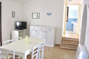 A compact living space with a dining area, a television, and a kitchen area.