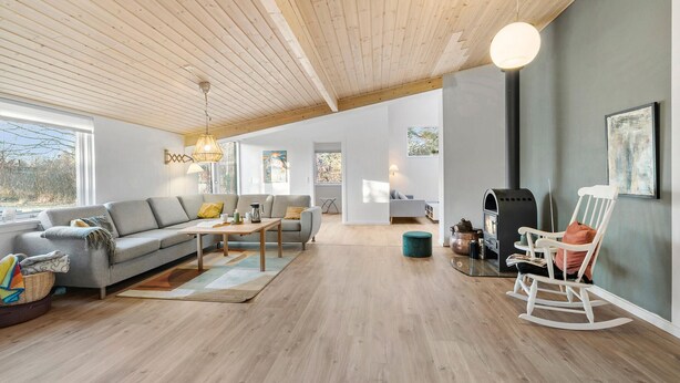 A modern living room with a wooden ceiling, a fireplace, and a rocking chair. - 4 bedroom awesome home in Storvorde (Storvorde)