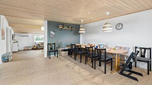 A spacious dining area with wooden flooring and a high ceiling. There are multiple dining tables with chairs, a clock on the wall, and a hanging light fixture. - 4 bedroom awesome home in Storvorde (Storvorde)