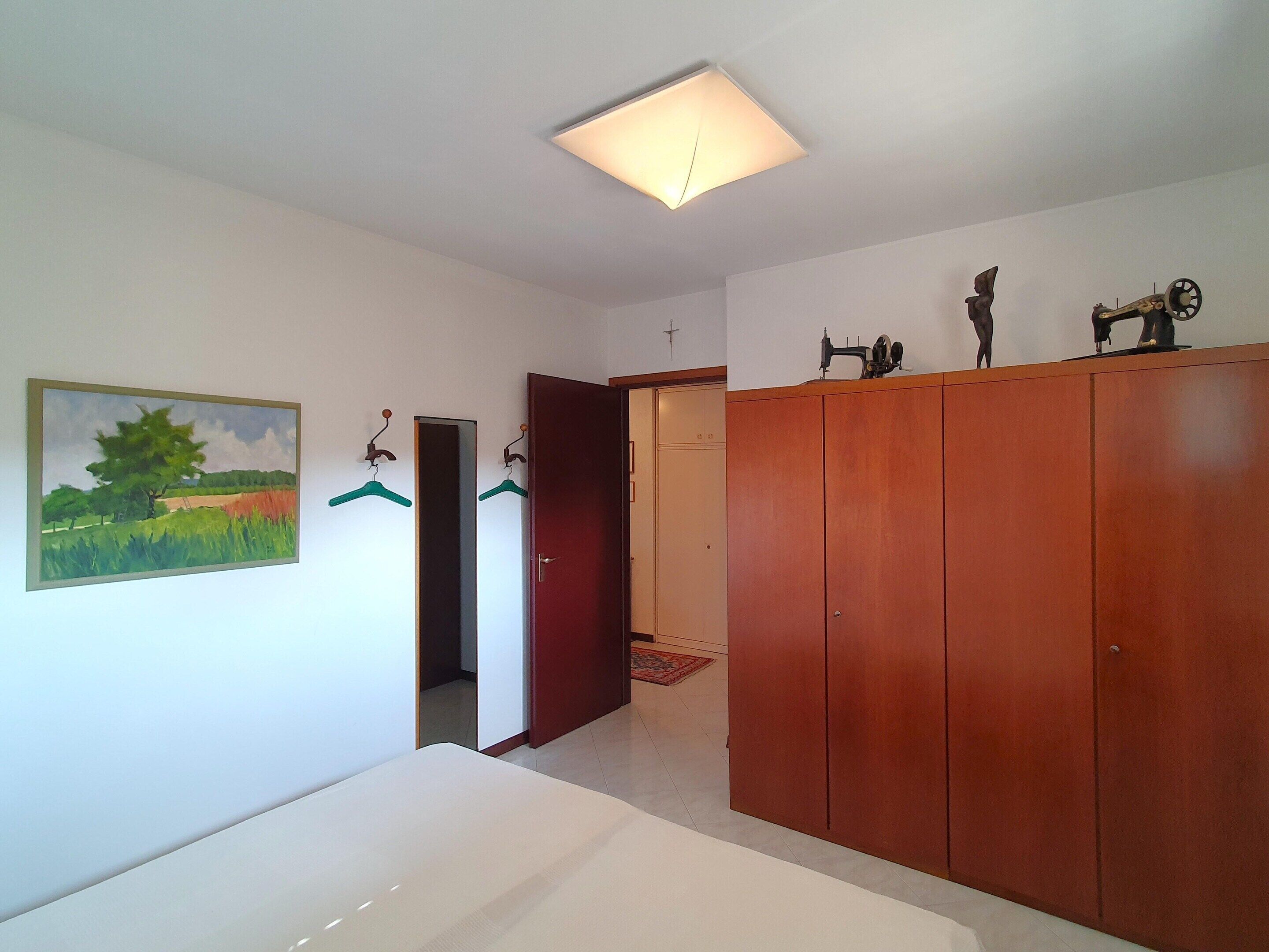 Une pièce comprenant un lit, une armoire, un tableau et un luminaire au plafond.