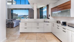 A modern kitchen with a central island, large windows, and a view of the city.