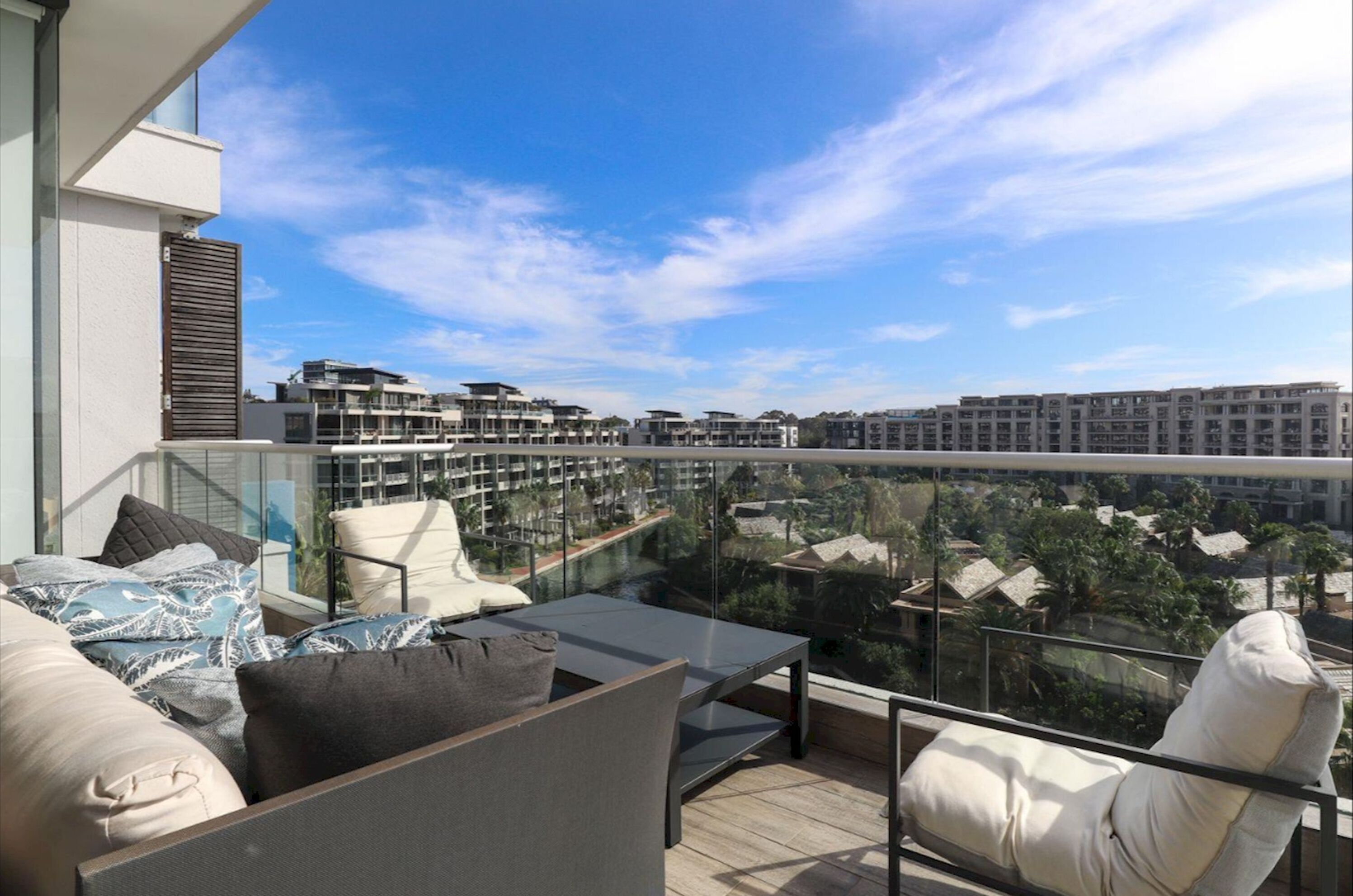 A balcony with a glass railing overlooking a residential area.