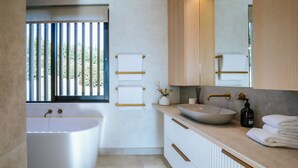 Un baño moderno con una bañera independiente, un lavamanos grande y un tocador con espejo.