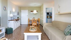 A cozy living room with a sofa, a coffee table, and a dining area with a table and chairs. - Coral Sunsent View With 1 Bedrooms and 1 5 Bathrooms (Tacoronte)