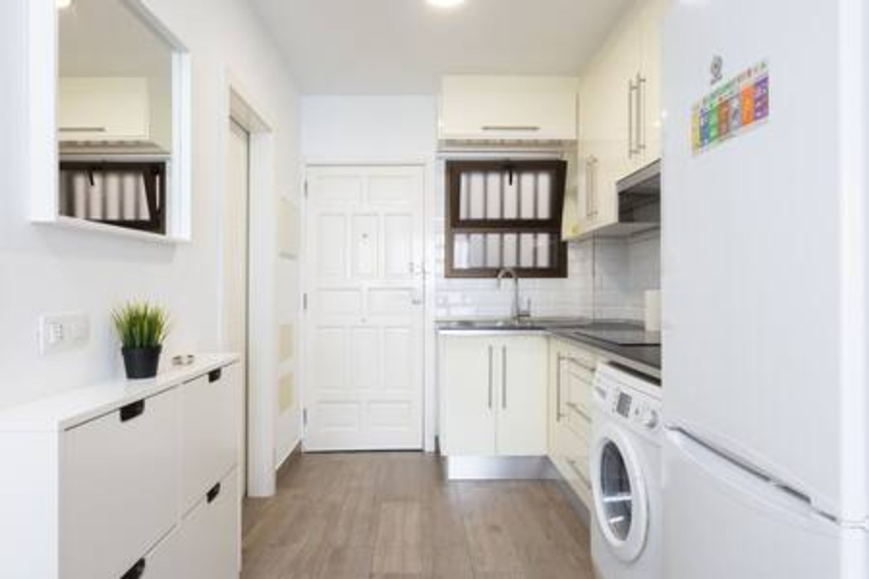 A compact kitchen with white cabinets, a built-in oven, and a washing machine.