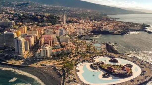 An aerial view of a coastal city with a prominent marina, high-rise buildings, and a large circular park area. - Apartamento Atardecer Martianez (Puerto de la Cruz)