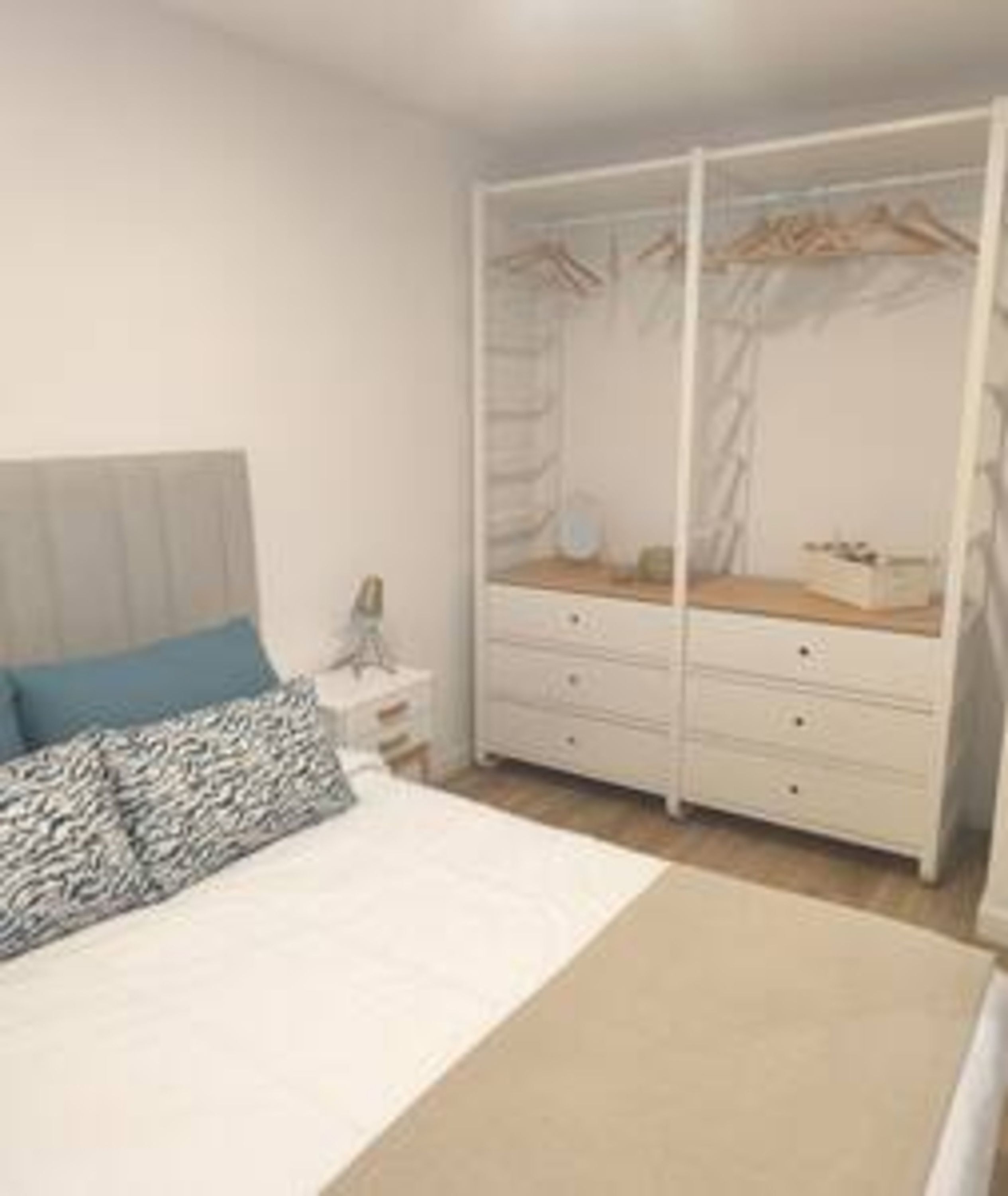 A bedroom with a bed, a bedside table, a dresser, and a wardrobe.