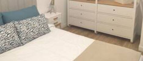 A bedroom with a bed, a bedside table, a dresser, and a wardrobe.