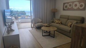 A modern living room with a sofa, coffee table, and a view of the outdoors. - Apartamento Atardecer Martianez (Puerto de la Cruz)