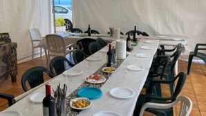 A long dining table set with plates, bowls, and bottles, surrounded by chairs. - Espectacular Villa con Piscina y Vistas al Valle (La Orotava)