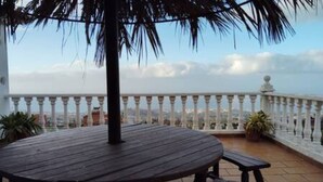 A wooden table and bench on a balcony with a white balustrade and a view of the city. - Espectacular Villa con Piscina y Vistas al Valle (La Orotava)