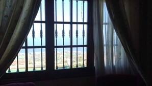A room with a large window featuring a metal grid design, curtains, and a view of a landscape. - Espectacular Villa con Piscina y Vistas al Valle (La Orotava)