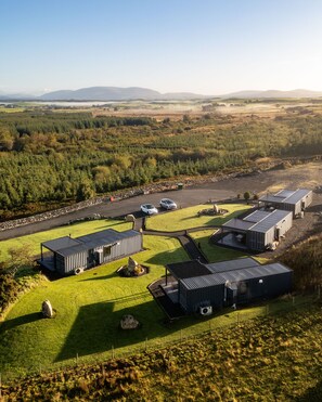 A rural property with multiple buildings, a parking area, and a view of the surrounding landscape.