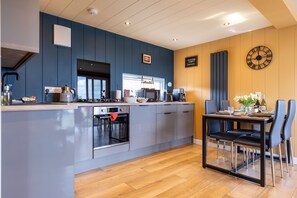 A modern kitchen with a central island, built-in appliances, and a dining area with a table and chairs.