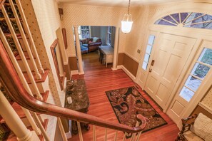A staircase leading to a living area with a wooden floor, a dining table, and a patterned rug.