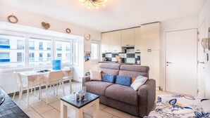 Un apartamento moderno con comedor, sofá, cocina y un ventanal grande.