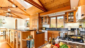 A modern kitchen with wooden cabinetry, a granite countertop, and a skylight. - oceanfront sanctuary michelin-adjacent & 180° view (Elk)