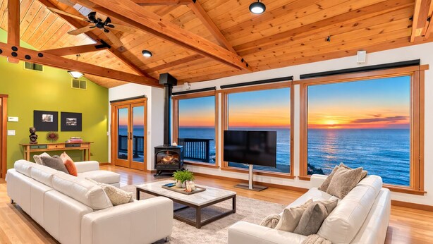 A spacious living room with a large window overlooking the sea, a fireplace, and a television. - oceanfront sanctuary michelin-adjacent & 180° view (Elk)