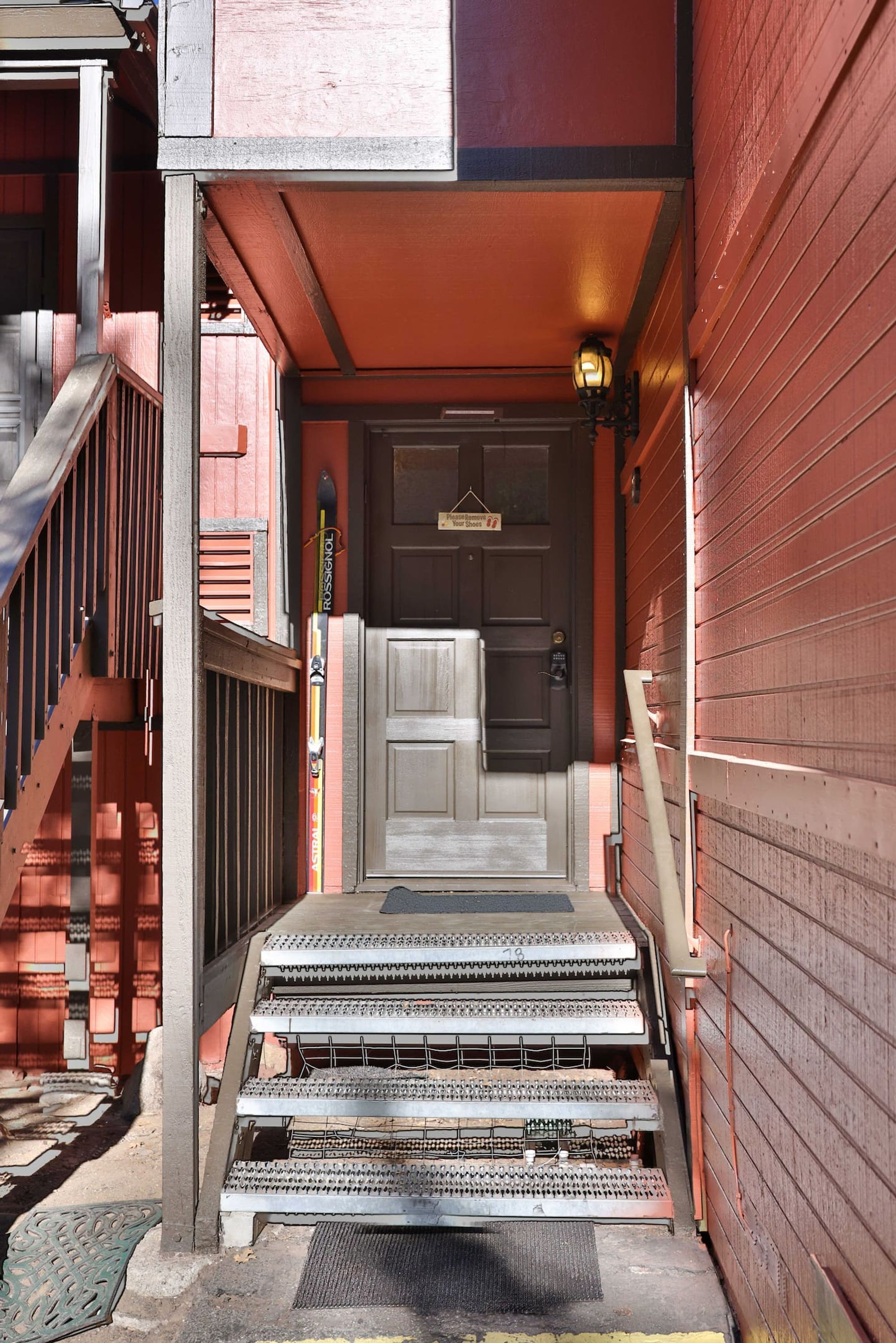 A narrow alleyway leading to a door with a metal staircase.