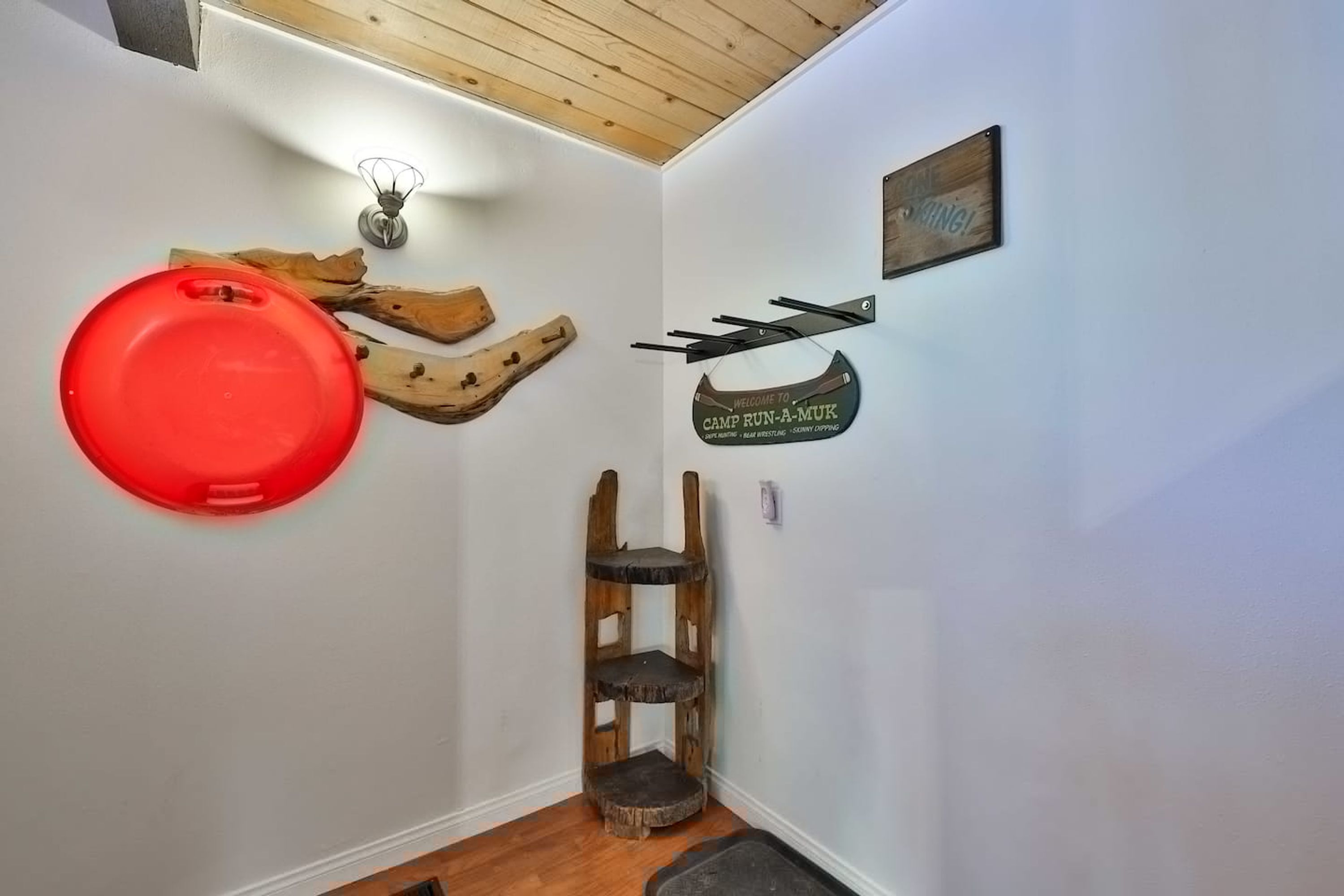 A corner of a room with a wooden shelf, a red object, and a welcome sign.