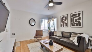 A modern living room with a sofa, coffee table, and a ceiling fan. - Normal Heights Hideaway (San Diego)