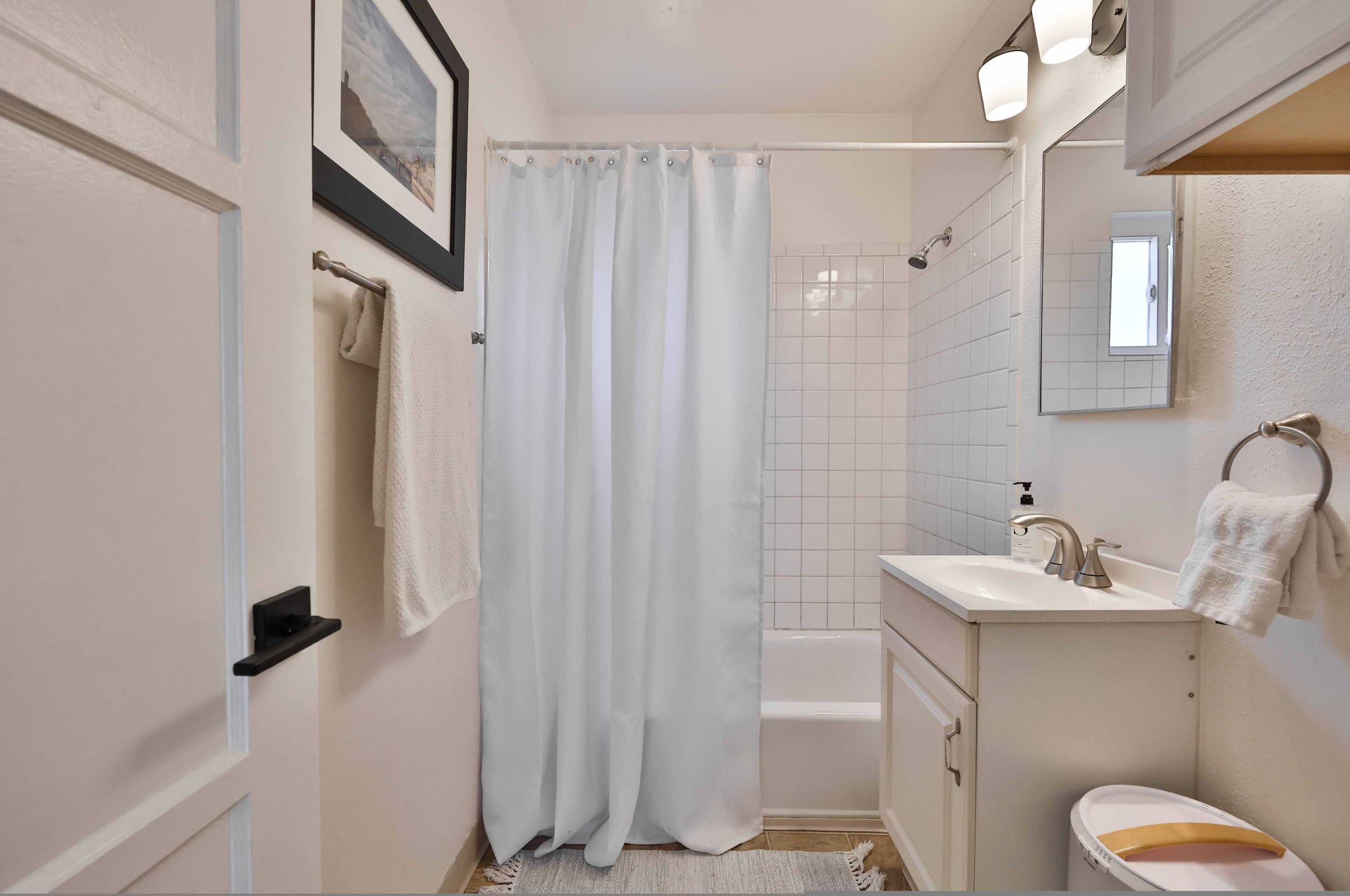 Une salle de bain avec une baignoire, un lavabo, des toilettes et un rideau de douche.