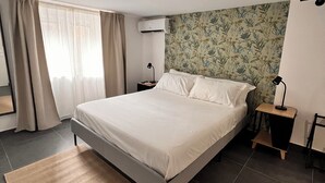 A modern bedroom with a large bed, a bedside table, a nightstand, a wall-mounted air conditioner, and a window with curtains. - Charming 2-bedroom house in lovely Catania with WiFi, AC (Catania)