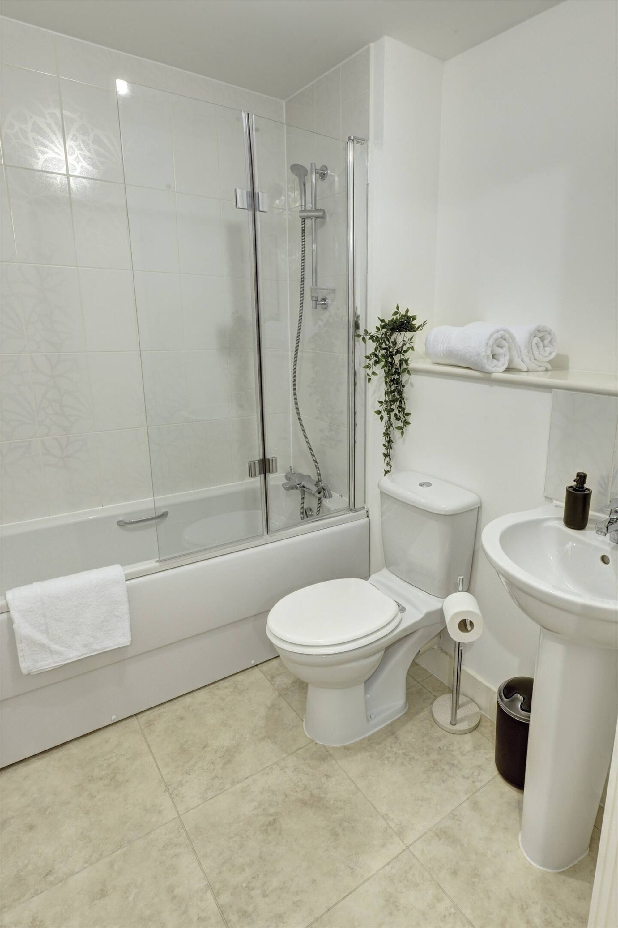 Un baño moderno con ducha envuelta en vidrio, inodoro y lavamanos.