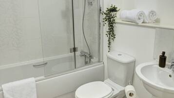 Un baño moderno con ducha envuelta en vidrio, inodoro y lavamanos.