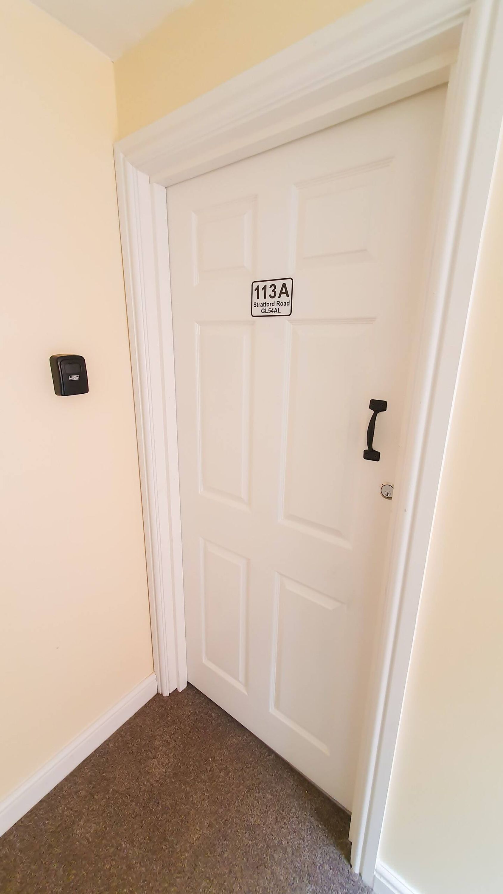 A closed white door with a sign reading "113A Stratford Road GL54AL".