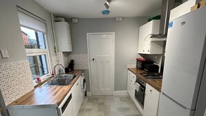 A modern kitchen with white cabinets, a wooden countertop, a built-in oven, and a refrigerator.