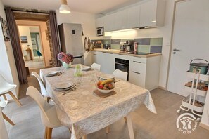Enjoy meals in this dining area with a table set for four, featuring a lace tablecloth and a bowl of fresh fruit.