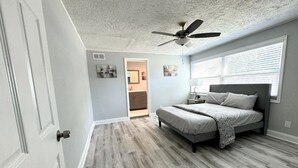 Une chambre à coucher avec un lit, un ventilateur de plafond et une fenêtre avec des stores.