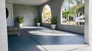 Un espace extérieur abrité, doté d’un sol en béton, de plantes en pot et offrant une vue sur la rue.