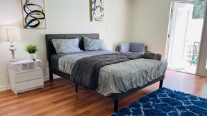 Ein Schlafzimmer mit Bett, Nachttischen, einer Lampe und abstrakter Wandkunst.