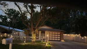 Ein Haus mit Garage, umgeben von einem weißen Zaun und Lichterketten.