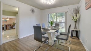 Un comedor moderno con una mesa de vidrio, sillas de metal y una lámpara en el techo.