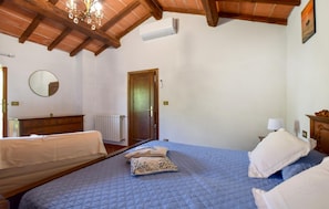 A bedroom with a wooden ceiling, a bed with blue bedding, a mirror, a radiator, and a door. - 2 bedroom beautiful home in Massarosa (Massarosa)