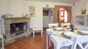 A dining area with a fireplace, a table set for four, and a brick archway leading to another room.