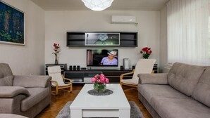 A modern living room with a flat-screen TV mounted on the wall, two sofas, a coffee table, and decorative vases. - Villa in Croatia Near Blue & Red Lakes (Imotski)