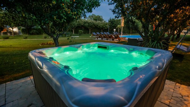 A hot tub in an outdoor setting with lounge chairs and a pool in the background. - Villa in Croatia Near Blue & Red Lakes (Imotski)