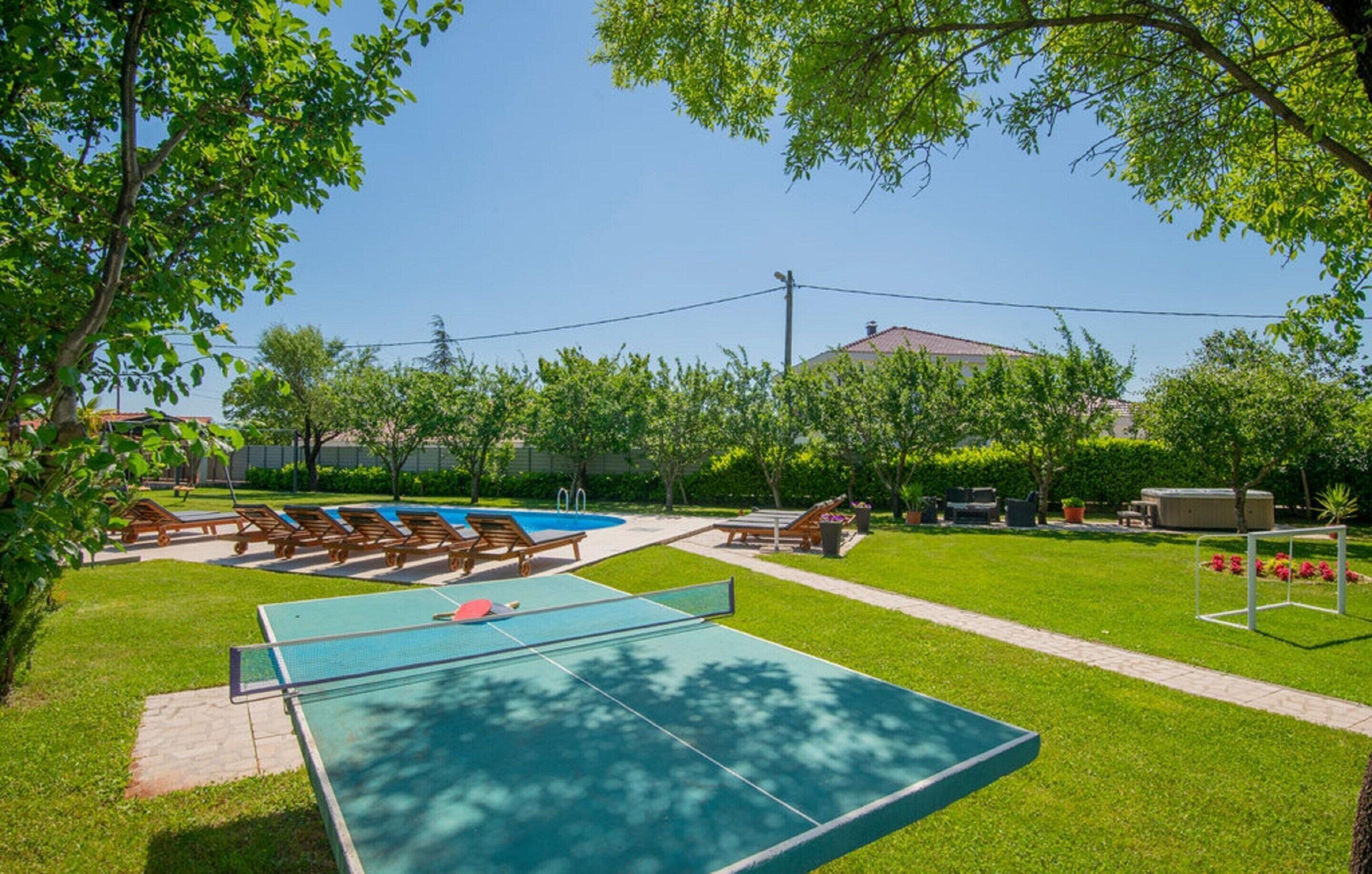 A backyard with a swimming pool, a ping pong table, and outdoor seating.
