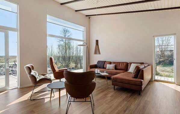 A spacious living room with a large window, a leather sofa, and a modern lamp.