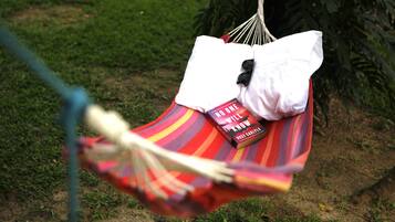 Una hamaca con un cojín a rayas y un libro titulado "No One Will Know" de Rose Garay.