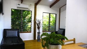Une pièce avec un canapé noir, une table à manger en bois et une plante en pot.