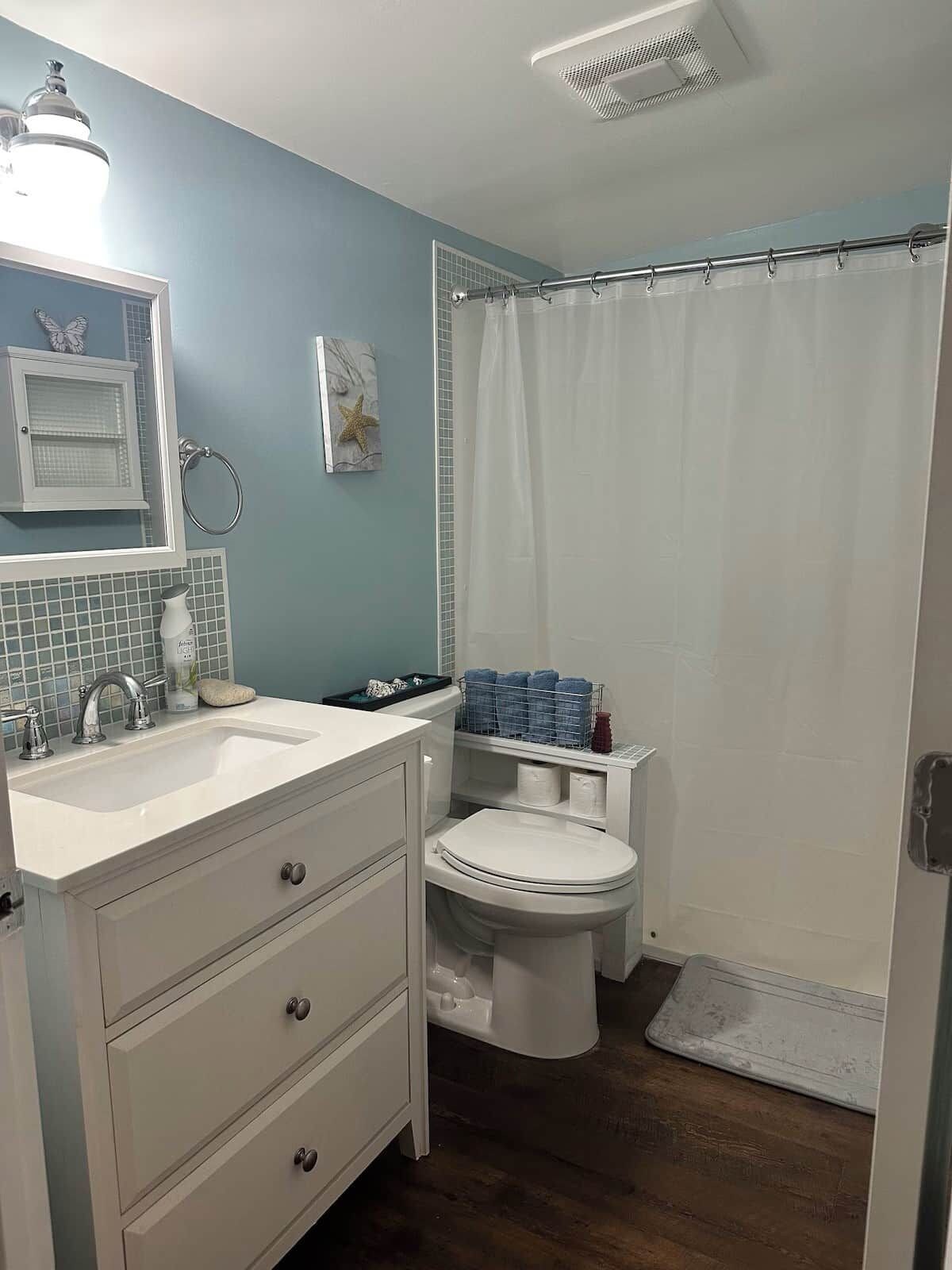 A bathroom with a sink, mirror, toilet, and shower curtain.