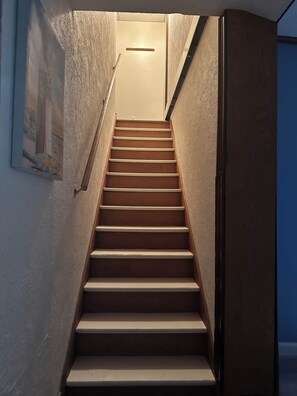 A staircase with a handrail, leading to a landing with a light fixture. - Spacious 4-bedroom house in charming Ransomville with WiFi (Ransomville)