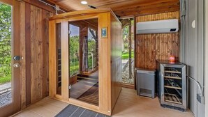 A wooden interior with a sauna, a glass door leading outside, and an air conditioning unit. - Astoria on Yellowstone (Sioux Falls)