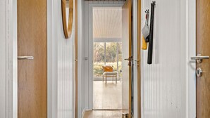 A hallway with wooden doors, a bench, and a view of an outdoor area with trees. - 3 bedroom awesome home in Ringkøbing (Ringkøbing)