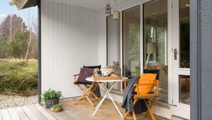 A wooden deck with two foldable chairs and a small table, a potted plant, and a view of the surrounding landscape. - 3 bedroom awesome home in Ringkøbing (Ringkøbing)